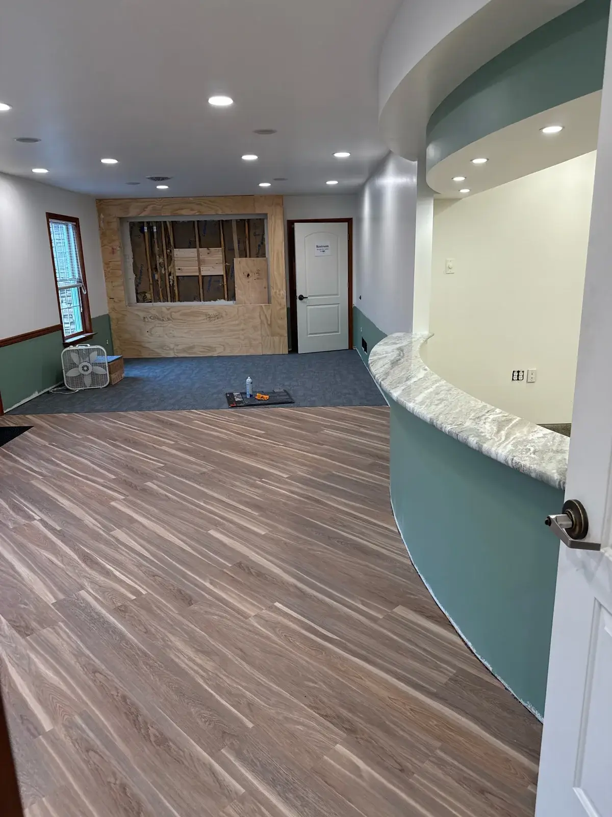 Curved reception desk with marble-look counter and new wood-look flooring inside the new Northumberland Hearing Center office under construction