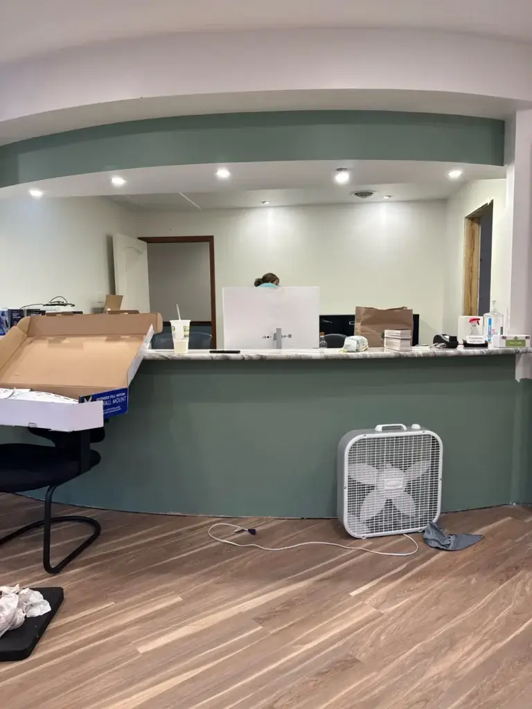 Curved front reception desk with sage green front and stone-look counter in Northumberland Hearing Center's new office